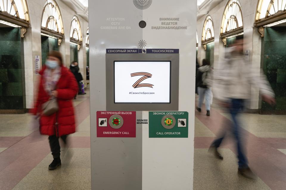 FILE - People walk past the letter Z, which has become a symbol of the Russian military, and a hashtag reading "We don't abandon our own" in an underground station in St. Petersburg, Russia, March 9, 2022. (AP Photo, File)