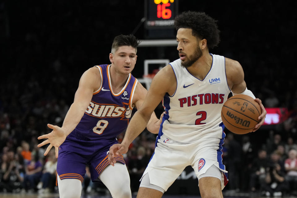 Detroit Pistons guard Cade Cunningham shields the ball from Phoenix Suns guard Grayson Allen (8) during the first half of an NBA basketball game, Wednesday, Feb. 14, 2024, in Phoenix. (AP Photo/Rick Scuteri)