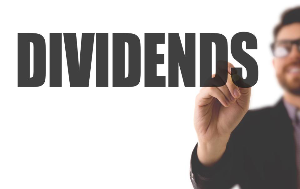 A person writing the word dividends.
