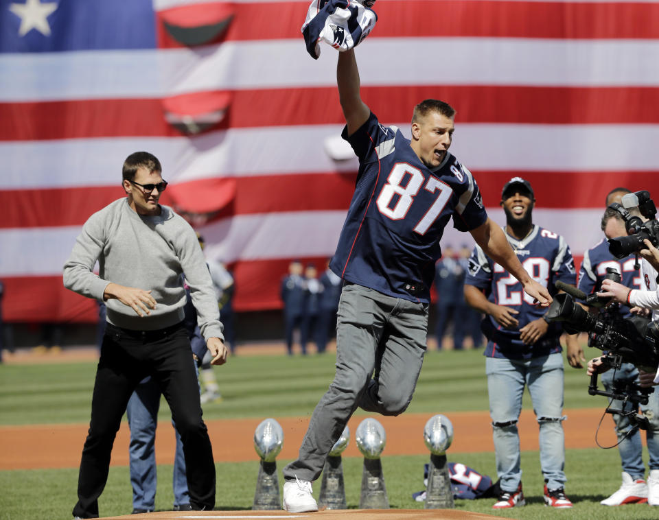 New England Patriots tight end Rob Gronkowski (87) runs with quarterback Tom Brady's, far left, recovered Super Bowl jersey as they joke around during Boston Red Sox home opening day ceremonies at Fenway Park, Monday, April 3, 2017, in Boston. The Red Sox face the Pittsburgh Pirates in the baseball game. (AP Photo/Elise Amendola)