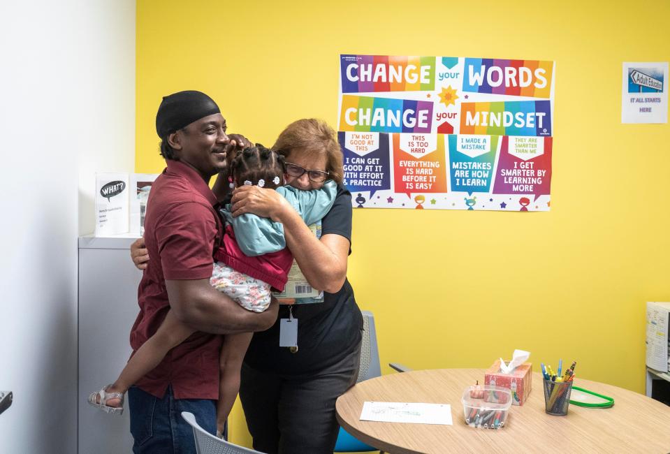 Tutor Janice Hamilton hugs Matalia Bush with her dad, Marquis Bush at The Lord's Place new 25,000-square-foot client service center at Fortin Family Campus celebrated with a ribbon cutting on October 19, 2023 in West Palm Beach, Florida. The center opened and began serving clients in early June.