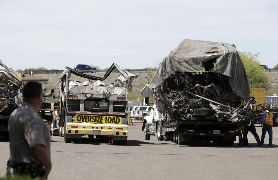 A California Highway Patrol officer stands at a gate as the demolished remains of a FedEx truck sit in a CalTrans maintenance station in Willows, Calif., Friday, April 11, 2014. At least ten people were killed and dozens injured in the fiery crash on Thursday, April 10, between a FedEx truck and a bus carrying high school students on a visit to a Northern California college. (AP Photo/Jeff Chiu)