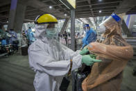 A public health worker helps Chinese tourists from Shanghai who arrived at Suvarnabhumi airport on special tourist visas, in Bangkok, Thailand, Tuesday, Oct. 20, 2020. Thailand on Tuesday took a modest step toward reviving its coronavirus-battered tourist industry by welcoming 39 visitors who flew in from Shanghai, the first such arrival since normal traveler arrivals were banned almost seven months ago. (AP Photo/Wason Wanichakorn)