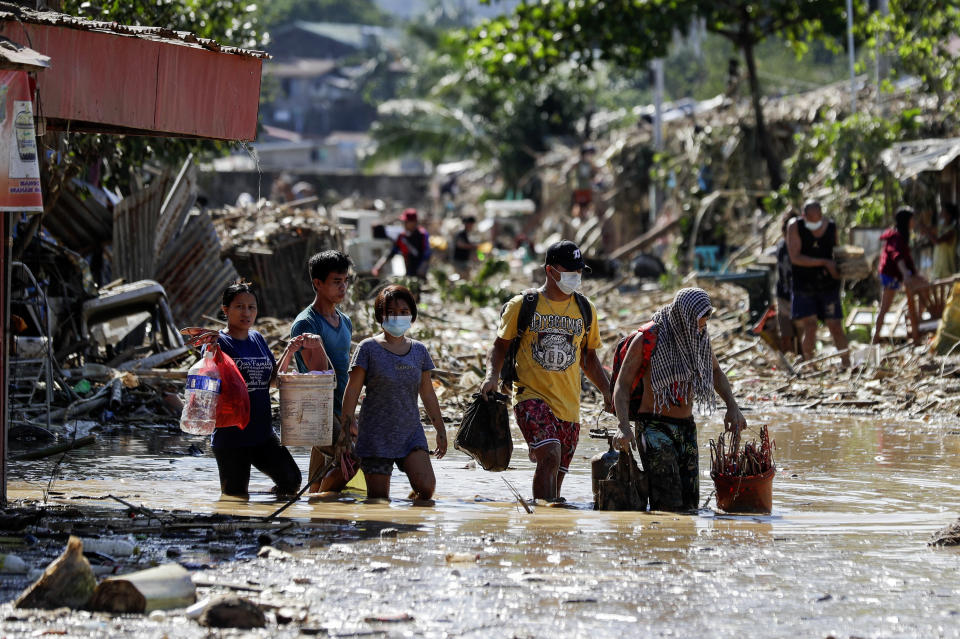 Residents walk on mud and debris as they retrieve belongings from their homes at the typhoon-damaged Kasiglahan village in Rodriguez, Rizal province, Philippines on Friday, Nov. 13, 2020. Thick mud and debris coated many villages around the Philippine capital Friday after Typhoon Vamco caused extensive flooding that sent residents fleeing to their roofs and killing dozens of people. (AP Photo/Aaron Favila)