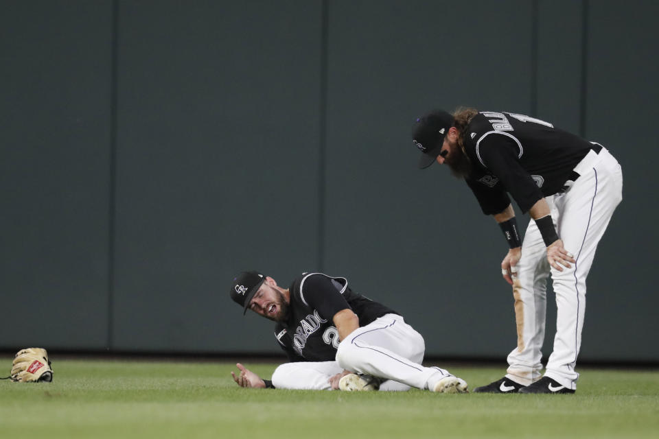 Colorado Rockies center fielder David Dahl, left, reacts after injuring his right leg while catching a lfy ball hit by San Francisco Giants' Scooter Gennett, as Rockies right fielder Charlie Blackmon stands next to him during the sixth inning of a baseball game Friday, Aug. 2, 2019, in Denver. Dahl was carted off the field. (AP Photo/David Zalubowski)