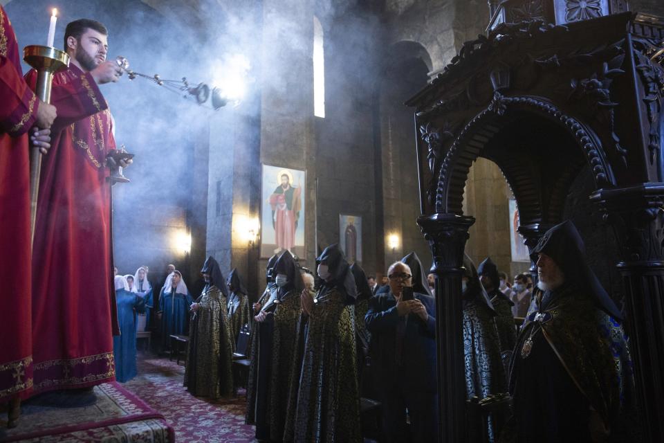 An Armenian Church priest conducts a service of remembrance for those killed in a war over the Nagorno-Karabakh region, at the Armenian Apostolic Cathedral in Etchmiadzin, the seat of the Oriental Orthodox church outside Yerevan, Armenia, Monday, Sept. 27, 2021. Azerbaijan and Armenia are marking the first anniversary of the start of their six-week war in which more than 6,600 people died and that ended with Azerbaijan regaining control of large swaths of territory. In Yerevan, the Armenian capital, thousands of people went to the Yerablur military cemetery to pay respects to soldiers buried there. (Grigor Yepremyan/PAN Photo via AP)