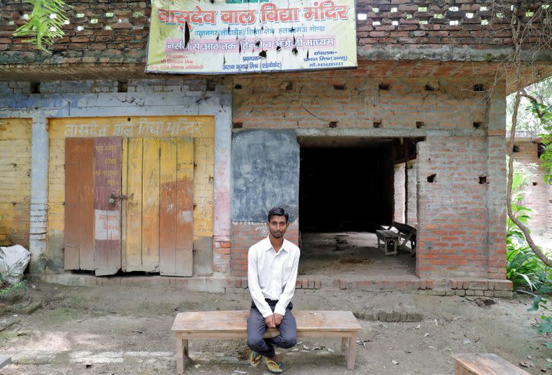 Ashish Kumar poses outside a primary school where he studied in Dutta Nagar