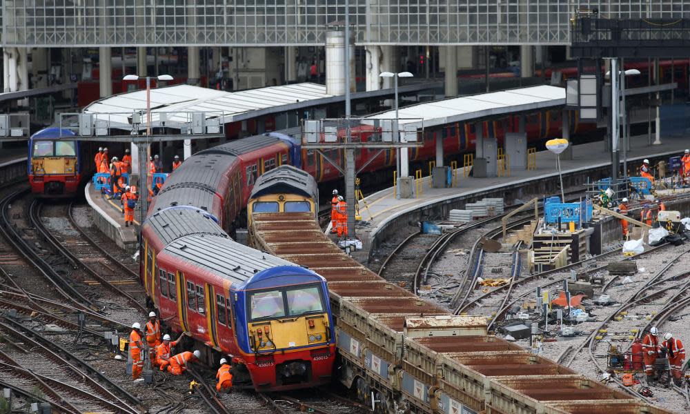 Workers examine a train that was partially derailed at Waterloo train station in London.