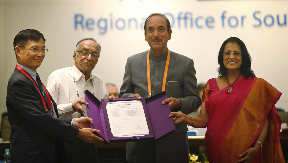 Chairperson of South-East Asia Regional Certification Commission for Polio Eradication Supamit Chunsuttiwat, left, and WHO's South-east Asian region Regional Director Poonam Khetrapal, right, give polio free certification to Indian Health Minister Ghulam Nabi Azad, second right, and Indian official P.K Umashankar, second left, in New Delhi, India, Thursday, March 27, 2014. The World Health Organization has formally declared India polio-free, with no new case of the disease detected in the country in the past three years. (AP Photo/Saurabh Das)