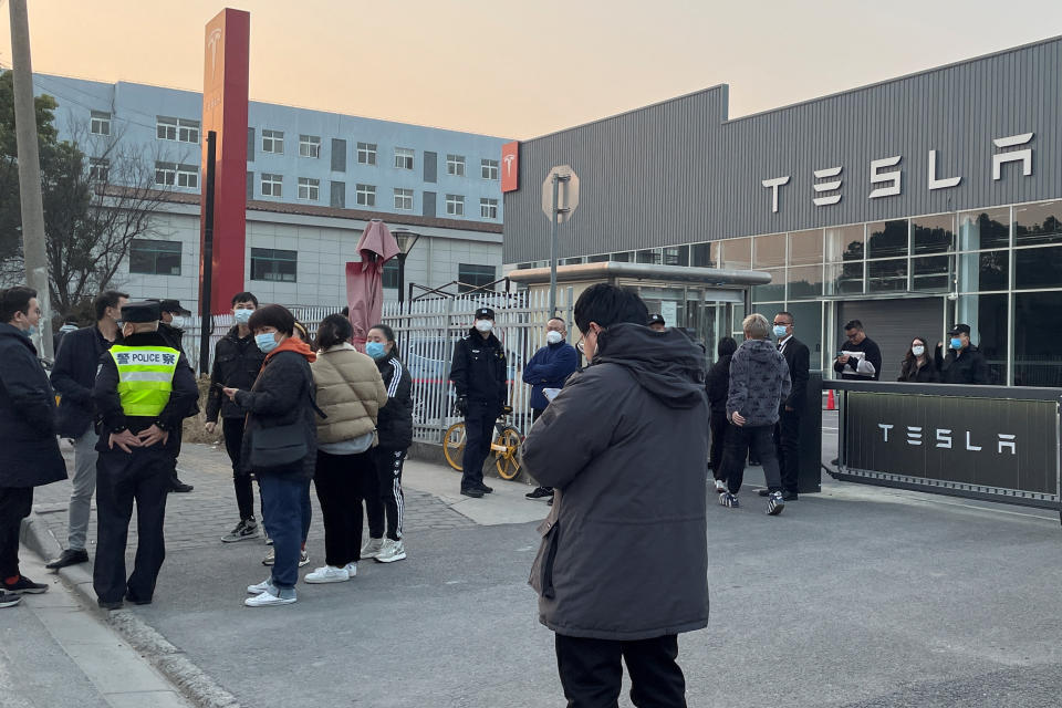People walk out from a building as police officer stands near the entrance, after demonstrating at the Tesla delivery centre in Shanghai, China January 7, 2023. REUTERS/Brenda Goh