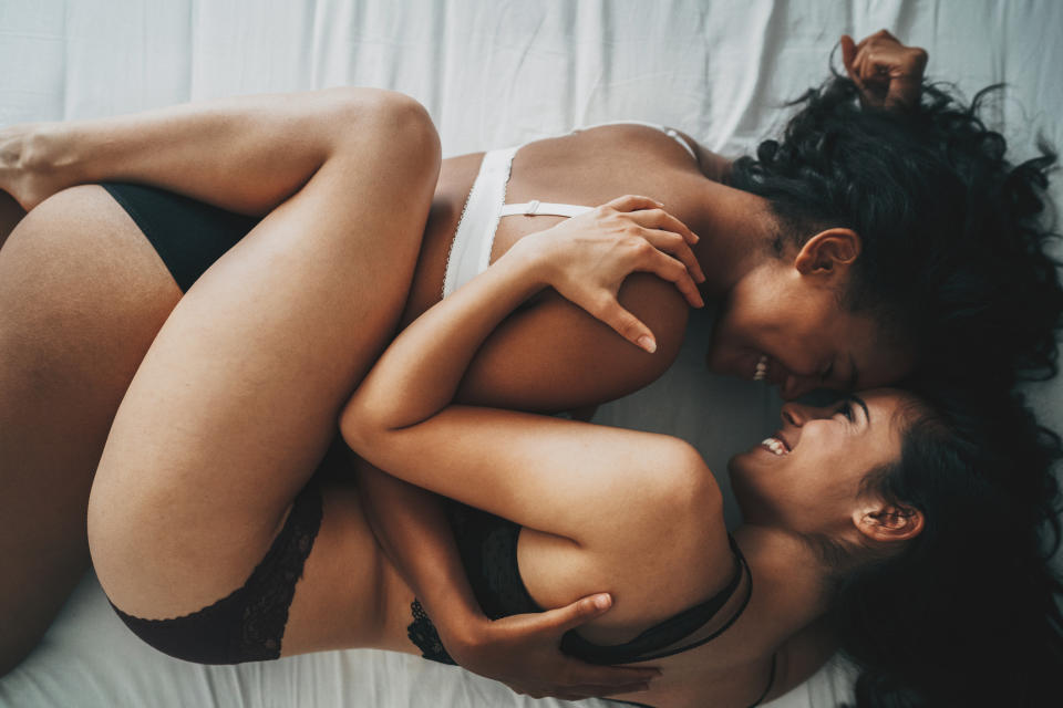 Two people embracing in intimate pose on bed, expressing closeness and affection