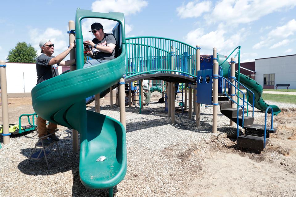 Volunteers Brandon Harrison, left, and Derek Sanderson build a SpyroSlide on the new playground at Hortonville Elementary School in Hortonville.
