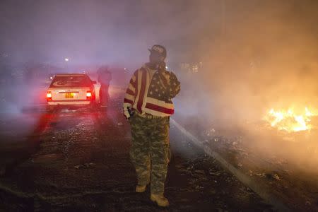 George Kiru, 36, walks past burning rubbish in Dandora, Nairobi, Kenya, June 14, 2015. REUTERS/Siegfried Modola