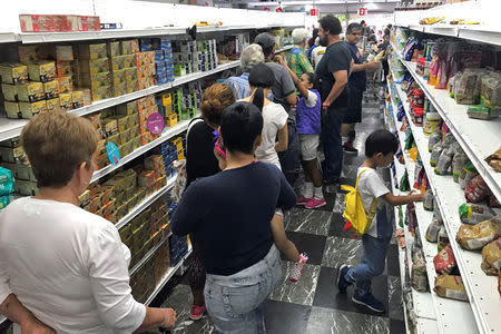 People wait in line to pay for products at a supermarket in Caracas, Venezuela August 18, 2018. REUTERS/Carlos Garcia Rawlins