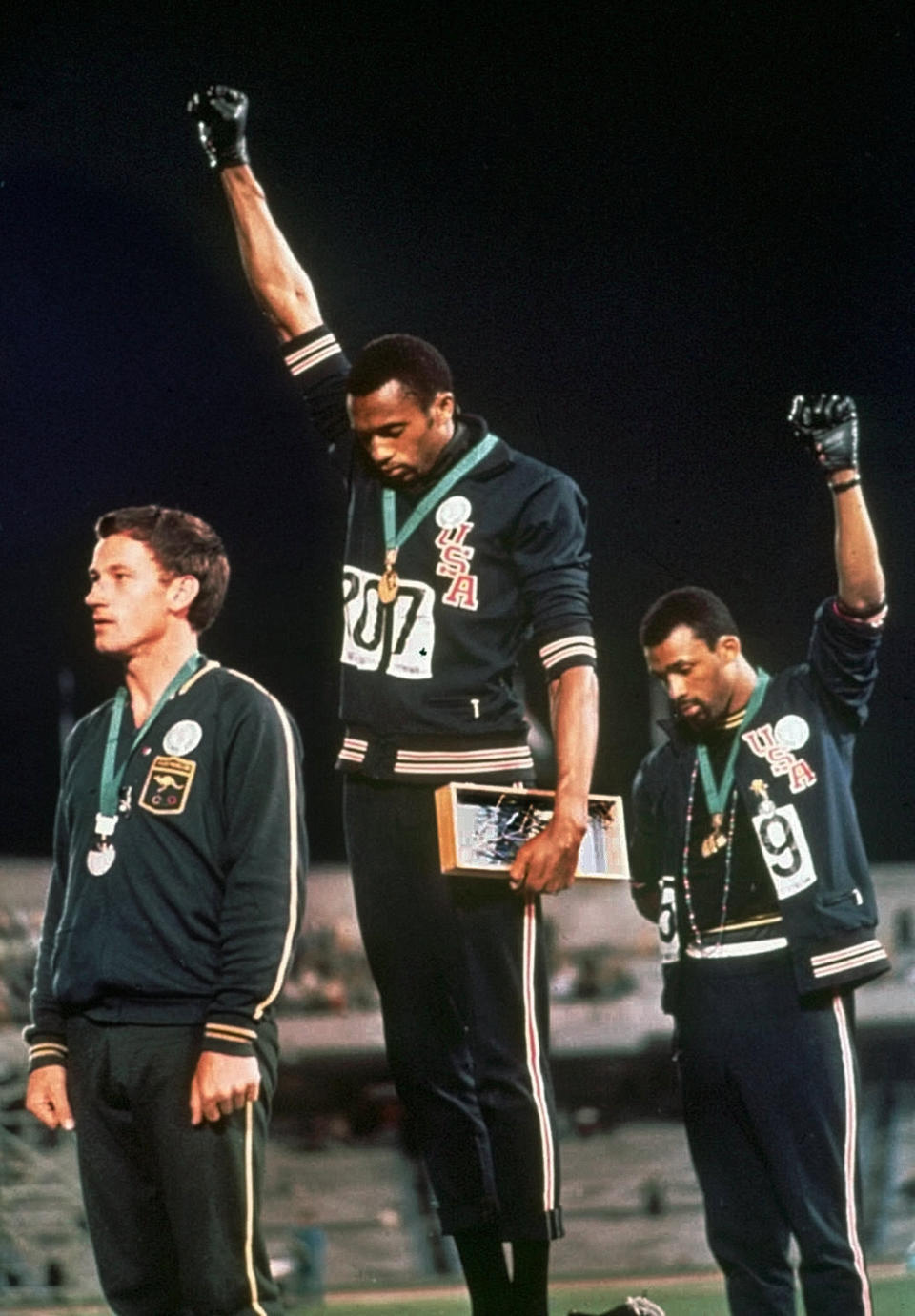 FILE - In this Oct. 16, 1968, file photo, U.S. athletes Tommie Smith, center, and John Carlos stare downward and extend gloved hands skyward in a Black power salute after Smith received the gold and Carlos the bronze for the 200 meter run at the Summer Olympic Games in Mexico City. Australian silver medalist Peter Norman is at left. Tommie Smith and John Carlos are part of the 2019 U.S. Olympic and Paralympic Hall of Fame class that will be inducted later this year.(AP Photo, File)