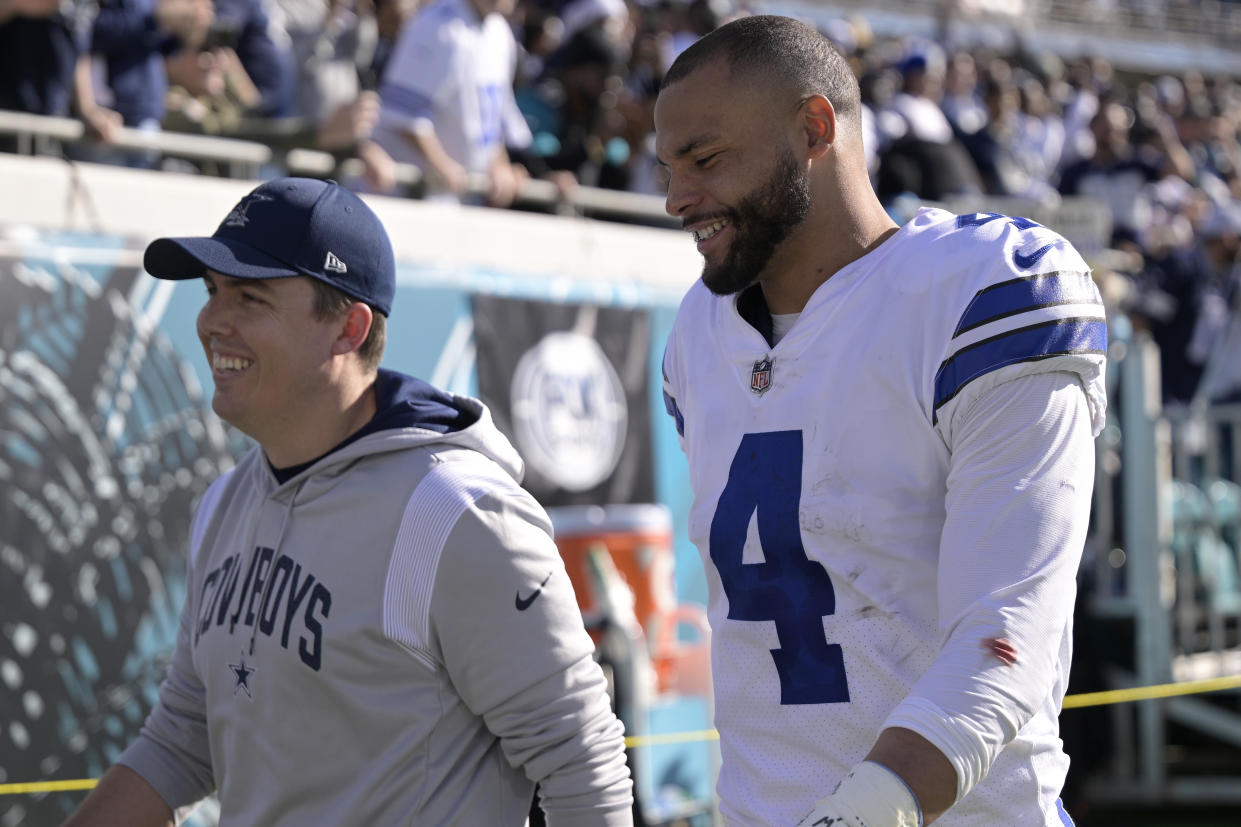 Dallas Cowboys quarterback Dak Prescott (4) and offensive coordinator Kellen Moore leave the field after the first half of an NFL football game against the Jacksonville Jaguars, Sunday, Dec. 18, 2022, in Jacksonville, Fla. (AP Photo/Phelan M. Ebenhack)