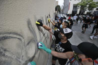 Volunteers clean graffiti from a store wall Monday, June 1, 2020, in Santa Monica, Calif., a day after unrest and protests over the death of George Floyd, a black man who died in police custody in Minneapolis. Floyd died after being restrained by Minneapolis police officers on May 25. (AP Photo/Marcio Jose Sanchez)