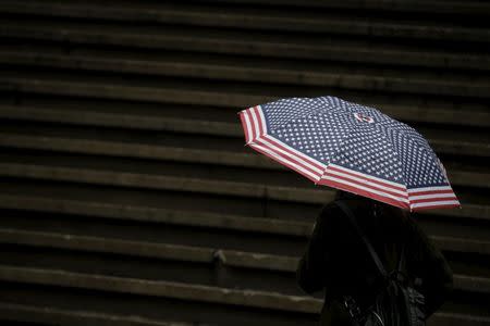 A tourist carries an unmbrella during a rain storm on Wall St. in New York's financial district February 24, 2016. REUTERS/Brendan McDermid