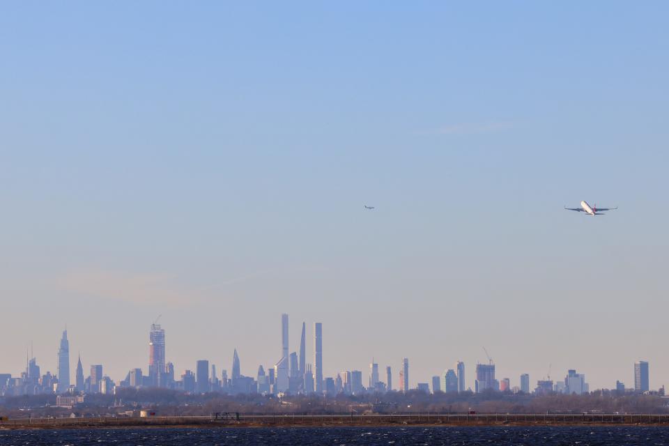 A passenger aircraft takes off from JFK international Airport in New York as the Manhattan skyline looms in the distance on February 5, 2024.