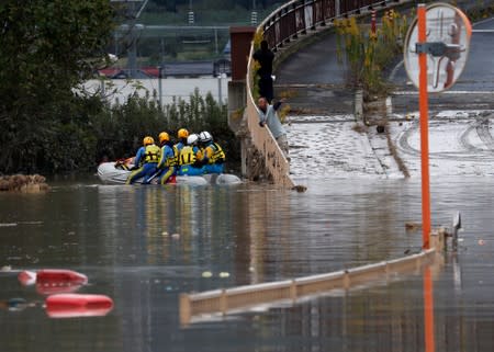 A man talks with rescue workers searching a flooded area in the aftermath of Typhoon Hagibis, which caused severe floods at the Chikuma River in Nagano