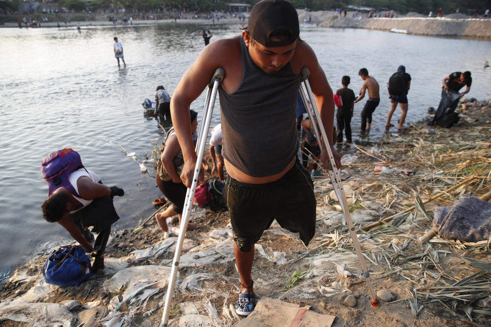 Un migrante hondureño discapacitado al que le falta una pierna regresa a la orilla guatemalteca del río Suchiate, en la frontera con México en Tecun Uman, Guatemala, el lunes 20 de enero de 2020. (AP Foto/Moisés Castillo)