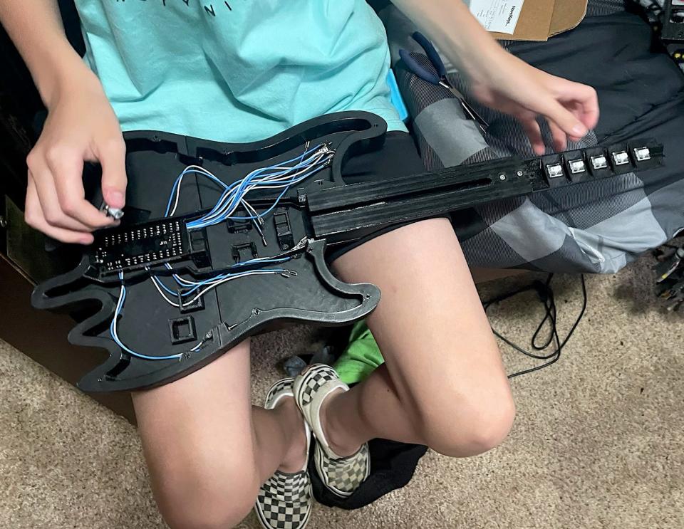 Alex Williams displays the Guitar Hero guitar he created with a 3D printer and wires from Amazon.