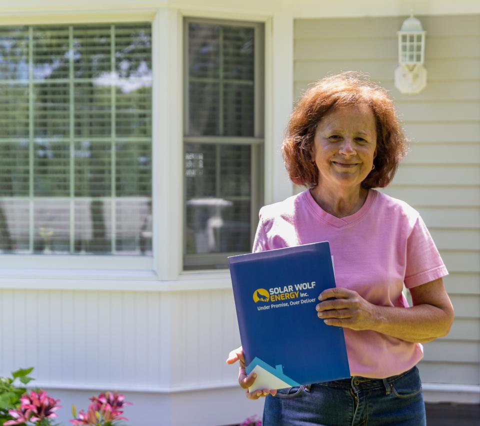 Pam Rego stands in front of her Yarmouthport house holding the signed contract of the Solar Wolf Energy Inc. in September 2021.