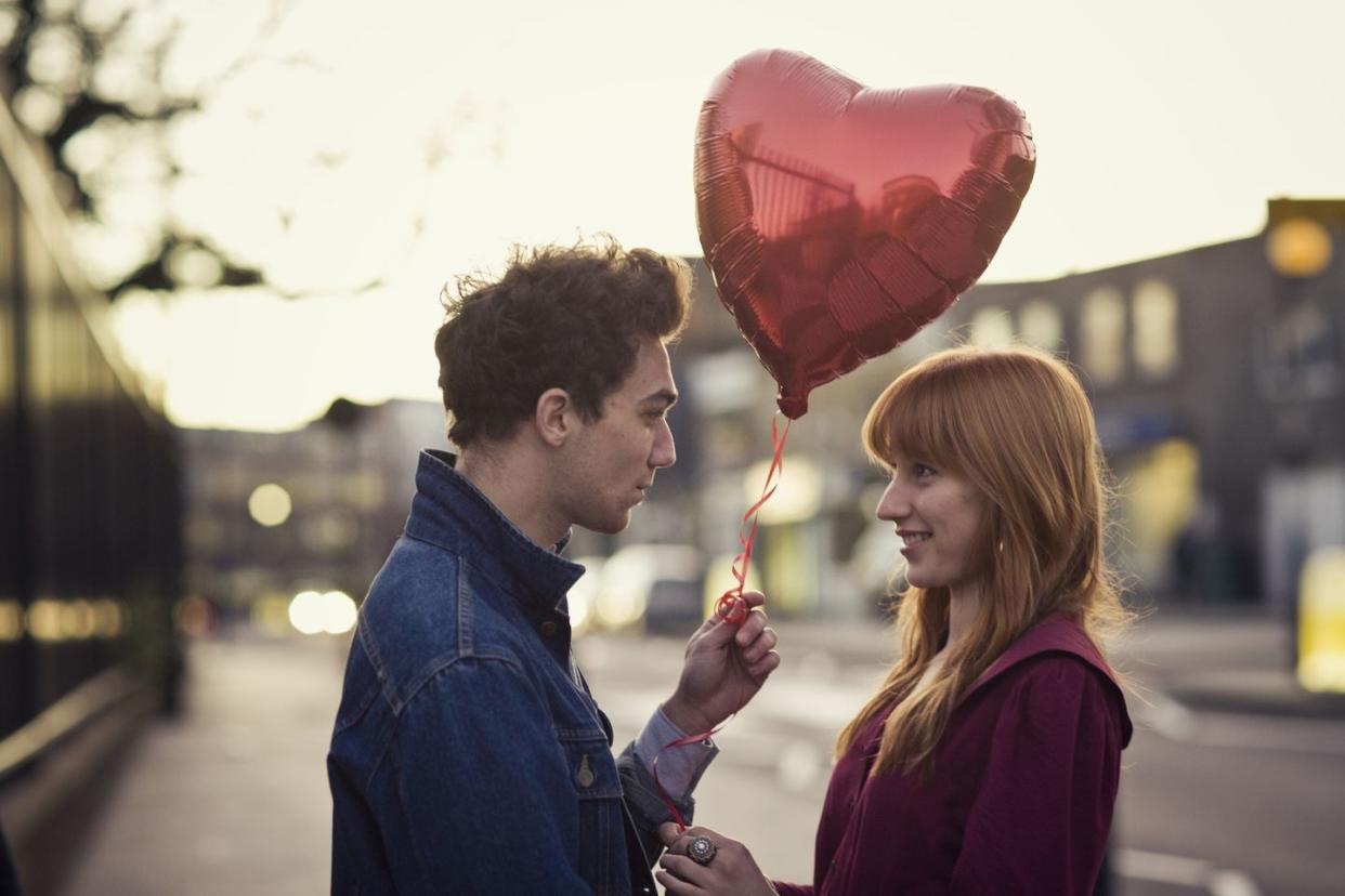 couple with man holding red heart shaped balloon