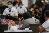 Staff wear face masks as they serve in a restaurant in Soho in London, Tuesday, Sept. 22, 2020. British Prime Minister Boris Johnson has slammed the brakes on the country's return to offices, saying people should work from home if possible to help slow the spread of the coronavirus. Johnson on Tuesday announced a package of new restrictions, including a requirement for pubs, restaurants and other hospitality venues in England to close between 10 p.m. and 5 a.m. (AP Photo/Frank Augstein)