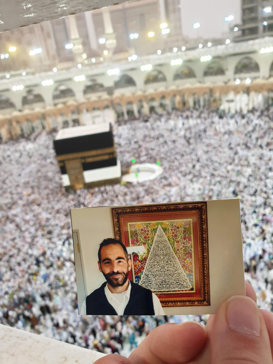 In this Aug. 6, 2019, photo provided by Aya Al-Umari, a photo of Al Noor mosque shooting victim, Hussein Al-Umari is held at the Great Mosque of Mecca, al-Ka bah al-Musharrafah by his sister Aya. Fifty-one people were killed and dozens more injured when a lone gunman attacked two mosques in Christchurch in 2019. New Zealanders on Sunday, March 15, 2020, will commemorate those who died on the first anniversary of the mass killing, as the tragedy continues to ripple through the community. Three people whose lives were forever altered that day say it has prompted changes in their career aspirations, living situations and in the way that others perceive them. (Aya Al-Umari via AP)