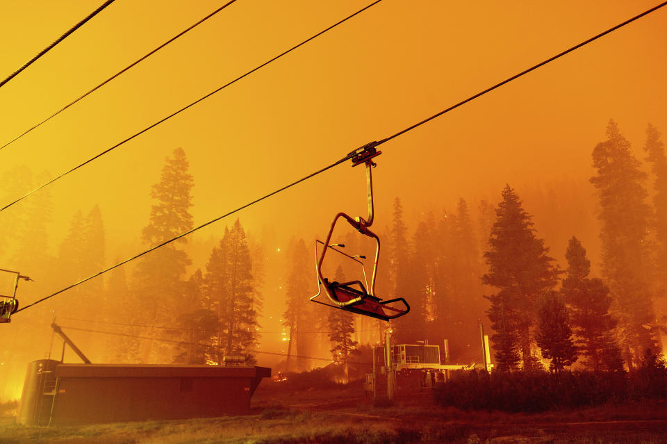 FILE - In this Sunday, Aug. 29, 2021 file photo, the Caldor Fire burns as a chair lift sits at the Sierra-at-Tahoe ski resort in Eldorado National Forest, Calif. The main buildings at the ski slope's base survived as the main fire front passed. Last week, managers overseeing the fight against the massive wildfire scorching California's Lake Tahoe region thought they could have it contained by the start of this week. Instead, on Monday, Aug. 30, 2021, the Caldor Fire crested the Sierra Nevada, forcing the unprecedented evacuation of all 22,000 residents of South Lake Tahoe. (AP Photo/Noah Berger, File)