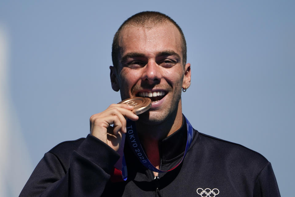 Bronze medalist Gregorio Paltrinieri, of Italy, bites his medal during a victory ceremony for the men's marathon swimming event at the 2020 Summer Olympics, Thursday, Aug. 5, 2021, in Tokyo, Japan. (AP Photo/Jae C. Hong)