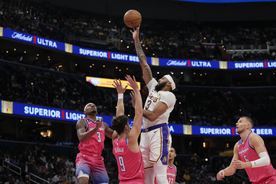 Los Angeles Lakers forward Anthony Davis, center, scores as Washington Wizards guard Bradley Beal, left, and forward Deni Avdija (9) defend during the first half of an NBA basketball game, Sunday, Dec. 4, 2022, in Washington. (AP Photo/Jess Rapfogel)