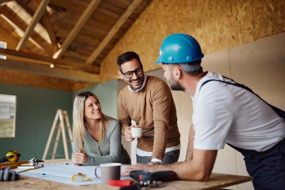 A couple consulting with a builder in a house under construction. 