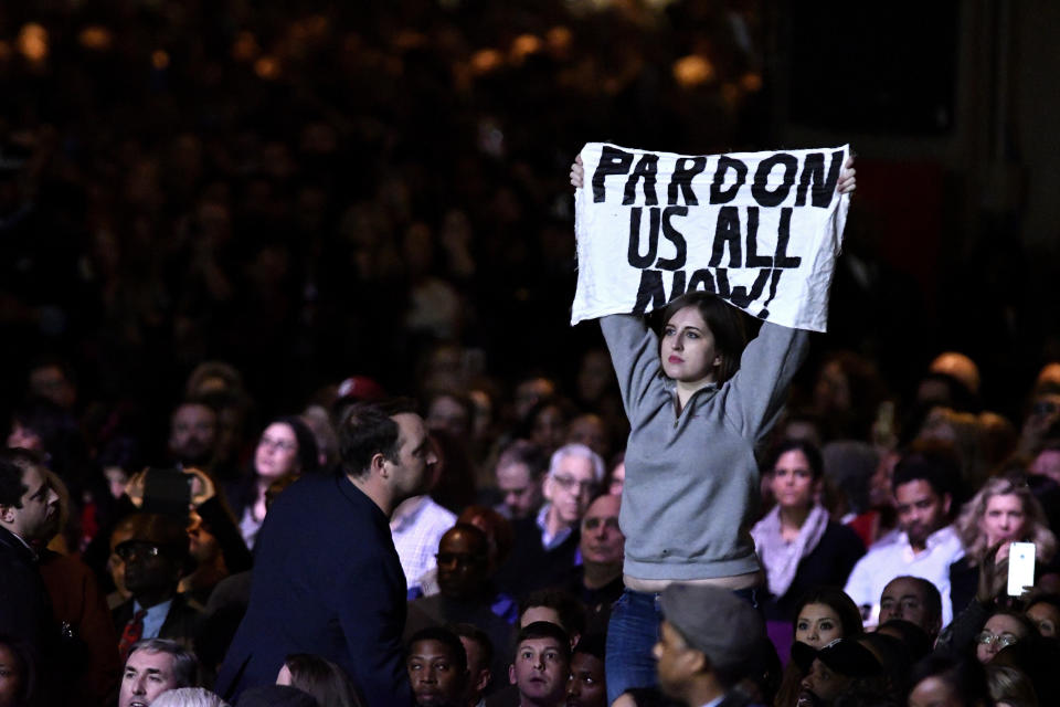 A protester holds up a sign reading "Pardon Us All Now!"