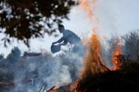 A Palestinian farmer burns grass as he cleans a field before picking up olives near the Israeli barrier in Salfit in the Israeli-occupied West Bank