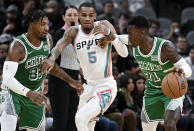 San Antonio Spurs' Dejounte Murray (5) tangles with Boston Celtics' Dennis Schroder (71) and Marcus Smart, left, during the first half of an NBA basketball game, Friday, Nov. 26, 2021, in San Antonio. (AP Photo/Darren Abate)