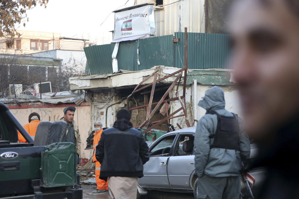 Afghan security forces personnel investigate the Friday's suicide attack and shooting in Kabul, Afghanistan, Saturday, Jan. 18, 2014. A suicide bomber blew himself up outside a Kabul restaurant, seen in the background, filled with foreigners and affluent Afghans, while two gunmen snuck in through the back door and opened fire Friday in a brazen dinnertime attack that killed 16 people, officials said. (AP Photo/Rahmat Gul)