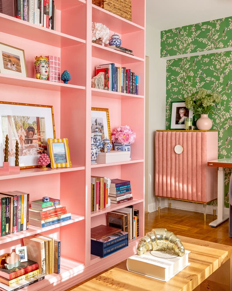 Pink bookshelf in colorful living room.