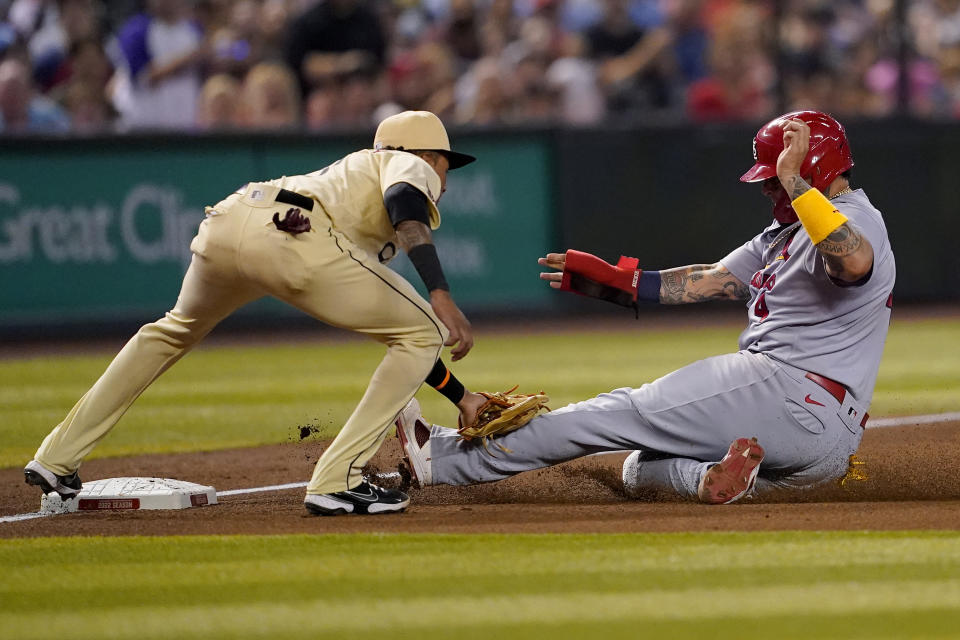 St. Louis Cardinals catcher Yadier Molina, right, is tagged out by Arizona Diamondbacks' Sergio Alcantara while advancing to third on a base hit by teammate Dylan Carlson during the fifth inning of a baseball game, Friday, Aug. 19, 2022, in Phoenix. (AP Photo/Matt York)