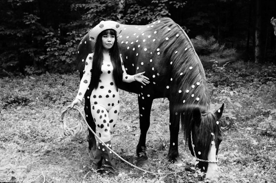 In this 1967 photo released by Yayoi Kusama Studio Inc., Japanese artist Yayoi Kusama poses with a horse in a happening titled "Horse Play" in Woodstock, New York. Kusama's signature splash of dots has now arrived in the realm of fashion in a new collection from French luxury brand Louis Vuitton - bags, sunglasses, shoes and coats. The latest Kusama collection is showcased at its boutiques around the world, including New York, Paris, Tokyo and Singapore, sometimes with replica dolls of Kusama. (AP Photo/Yayoi Kusama Studio Inc.) NO SALES, EDITORIAL USE ONLY, CREDIT MANDATORY