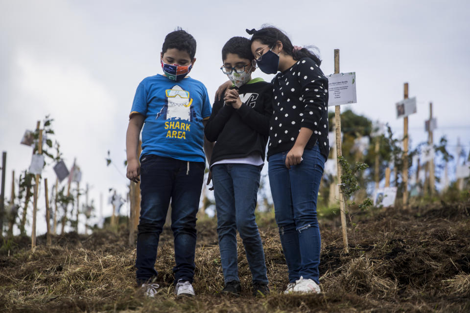 Grandchildren of Alejandro Navas, who died from complications related to COVID-19, stand together after spreading his cremated remains on a hill in the El Pajonal de Cogua Natural Reserve, north of Bogota, Colombia, Thursday, June 24, 2021. As Colombia suffers a critical moment of the pandemic, some families are bringing the cremated remains of their loved ones to the reserve where trees are planted along with the ashes in their honor. (AP Photo/Ivan Valencia)