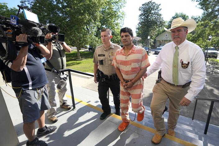 Francisco Oropeza, center, is escorted to the San Jacinto County courthouse by San Jacinto County Sheriff Greg Capers, right, for a hearing Thursday, May 18, 2023, in Coldspring, Texas. Oropeza is suspected of killing five people, including a 9-year-old boy, after neighbors asked him to stop firing off rounds in his yard. (AP Photo/David J. Phillip)