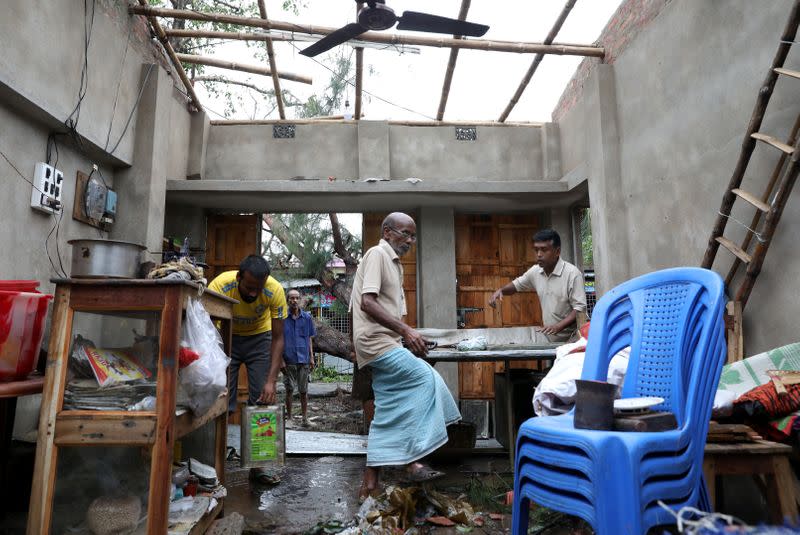 Men salvage items from a damaged shop after Cyclone Amphan made its landfall, in South 24 Parganas district