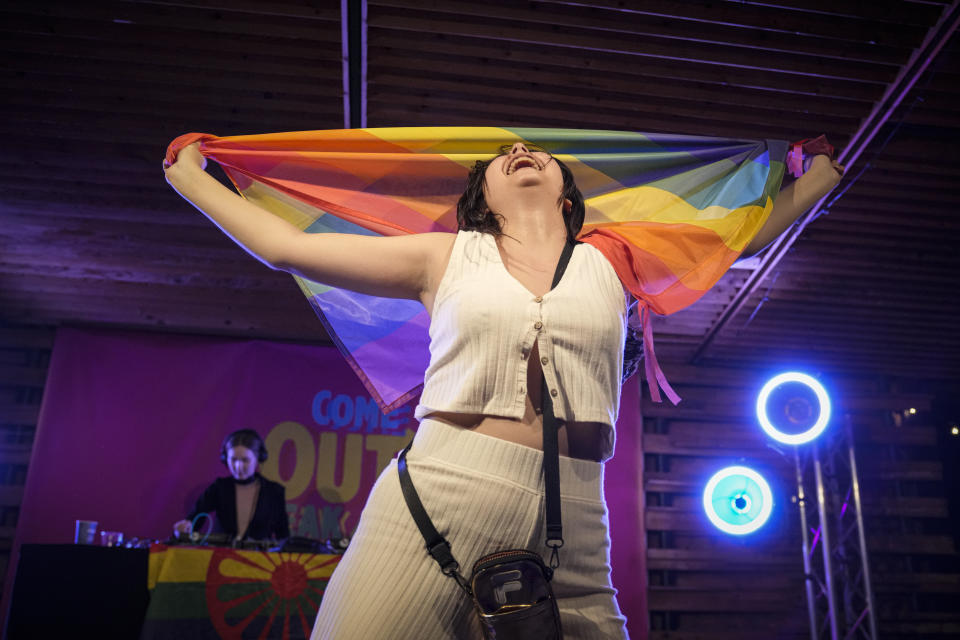 A spectator dances holding a rainbow flag at Pride Park, a venue for artistic shows ahead the Pride 2021 in Bucharest, Romania, Thursday, Aug. 12, 2021. The 20th anniversary of the abolishment of Article 200, which authorized prison sentences of up to five years for same-sex relations, was one cause for celebration during the gay pride parade and festival held in Romania's capital this month. People danced, waved rainbow flags and watched performances at Bucharest Pride 2021, an event that would have been unimaginable a generation earlier. (AP Photo/Vadim Ghirda)