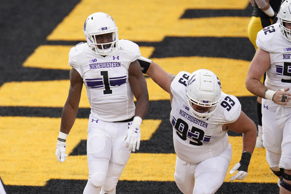 Northwestern running back Jesse Brown (1) celebrates with teammate Northwestern Joe Spivak (93) after scoring on a 2-yard touchdown run during the second half of an NCAA college football game against Iowa, Saturday, Oct. 31, 2020, in Iowa City, Iowa. (AP Photo/Charlie Neibergall)