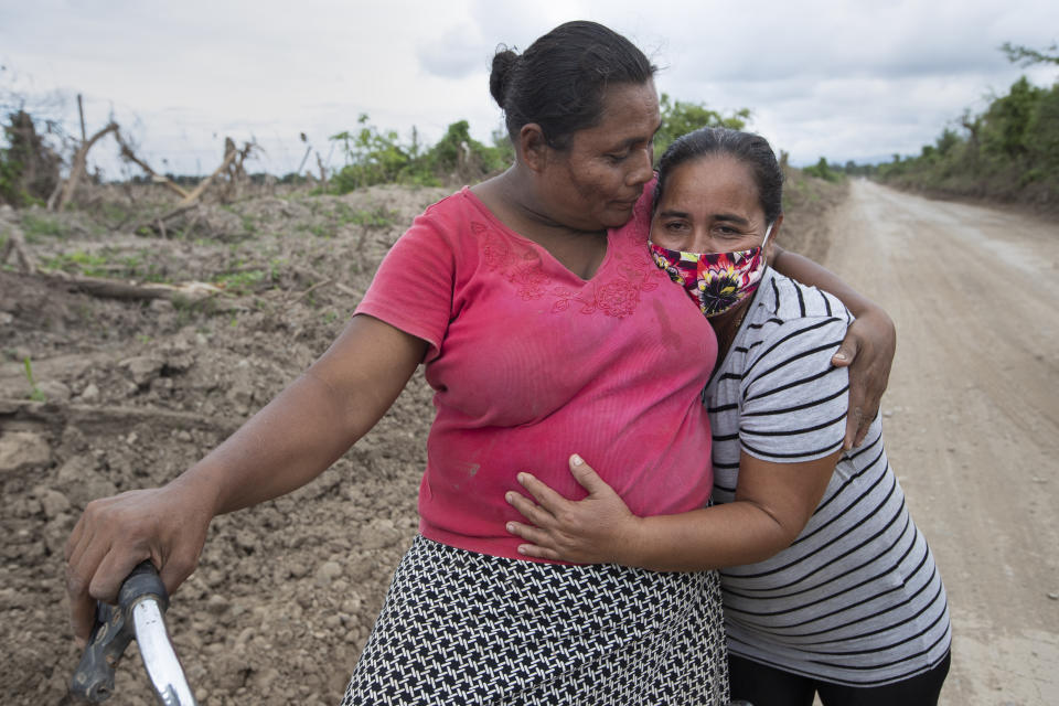 Xiomara Cruz, right, and Melinda Martínez reunite for the first time since last year's hurricanes Eta and Iota on the route to a banana plantation where they worked before last year's storms destroyed the area in La Lima, on the outskirts of San Pedro Sula, Honduras, Wednesday, Jan. 13, 2021. The devastation wrought by November's hurricanes and the economic damage of the COVID-19 pandemic has added to the forces of poverty and gang violence that drive Hondurans to migrate. (AP Photo/Moises Castillo)