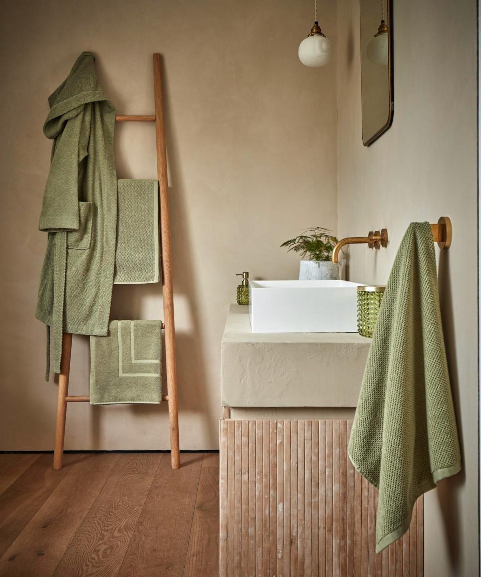 Neutral bathroom with green towels on ladder