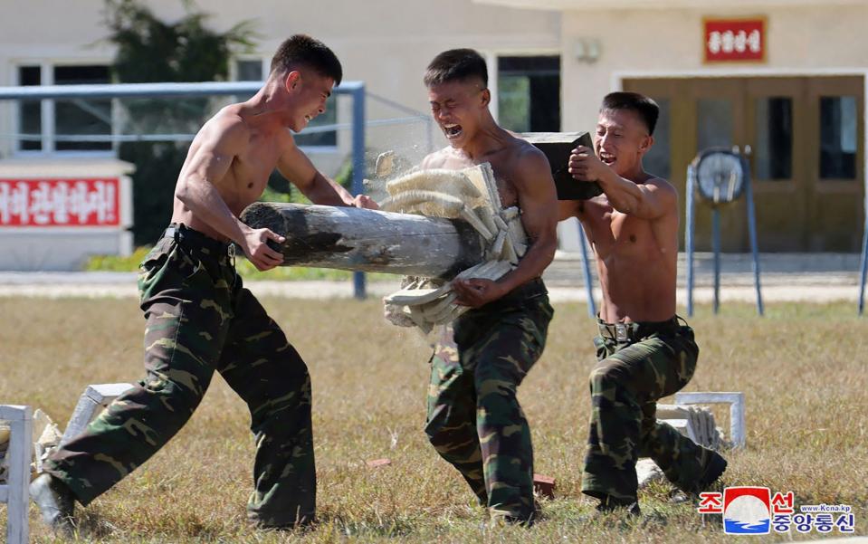 North Korean troops test out a fellow soldier's six-pack in a propaganda display