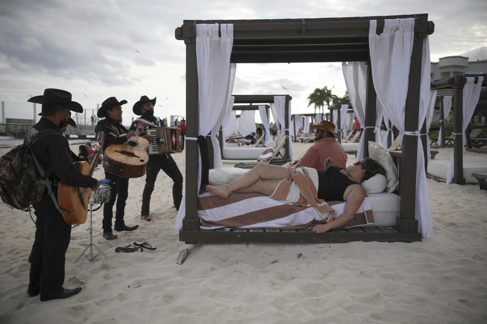 Roving musicians "Los Compas" serenade a couple on the shore of Mamitas beach, in Playa del Carmen, Quintana Roo state, Mexico, Tuesday, Jan. 5, 2021. Mexico saw a holiday bump in tourism amid the new coronavirus pandemic surge. (AP Photo/Emilio Espejel)